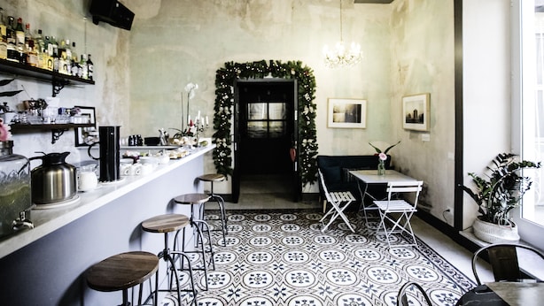 Zona de bar con taburetes, una barra con botellas y un suelo estampado.
