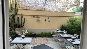 Un área de patio con mesas y sillas, un paraguas decorativo y una planta de cactus.