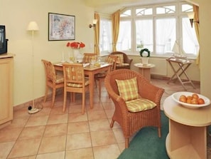 Un comedor con una mesa, sillas y un sillón de mimbre.