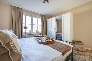 Hotellihuone, jossa on sänky, aamiaistarjoilu, ikkuna, vaatekaappi ja näkymä kaupunkiin.