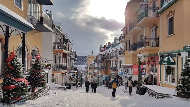 Eine verschneite Straße mit Gebäuden an beiden Seiten, mit Balkonen und Schaufenstern.