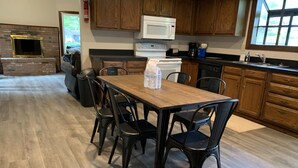 Une cuisine avec des meubles de rangement en bois, un four à micro-ondes, une cuisinière et une table à manger avec des chaises.