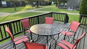 Une terrasse en bois avec une table ronde et six chaises rouges.