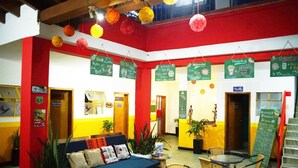 A brightly colored hotel lobby with a blue sofa, a small table, and a staircase. - Traveler Hostel (San Gil)