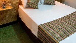 A hotel room with a bed, a stone headboard, a wall with three framed paintings, and two bedside lamps. - Traveler Hostel (San Gil)