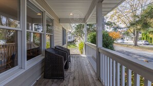 A covered porch with wicker chairs and a view of the street.