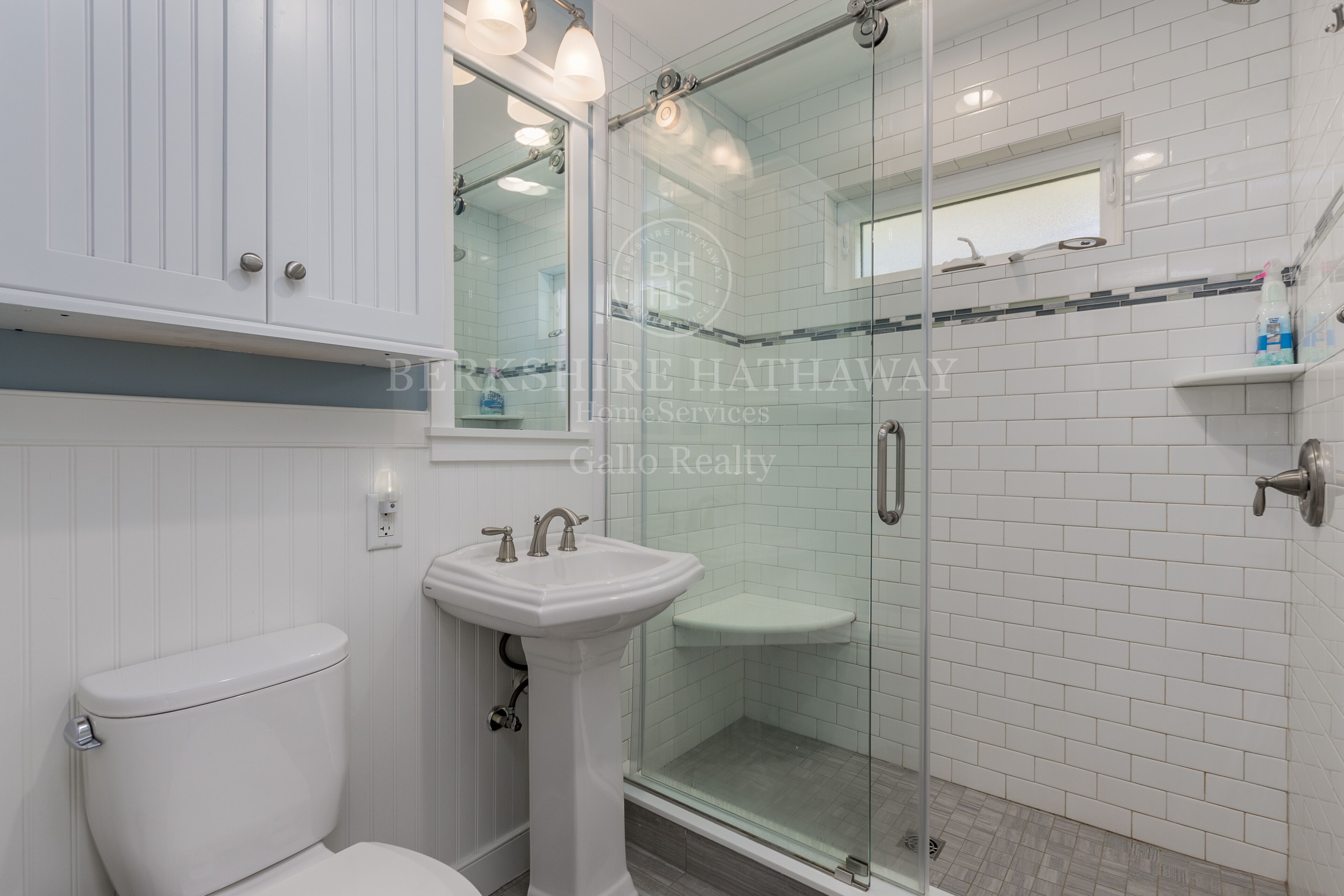 Une salle de bain équipée de toilettes, d’un lavabo sur colonne et d’une douche à parois de verre.