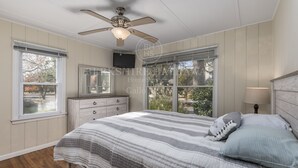 A bedroom with a bed, a ceiling fan, a dresser, and a window.