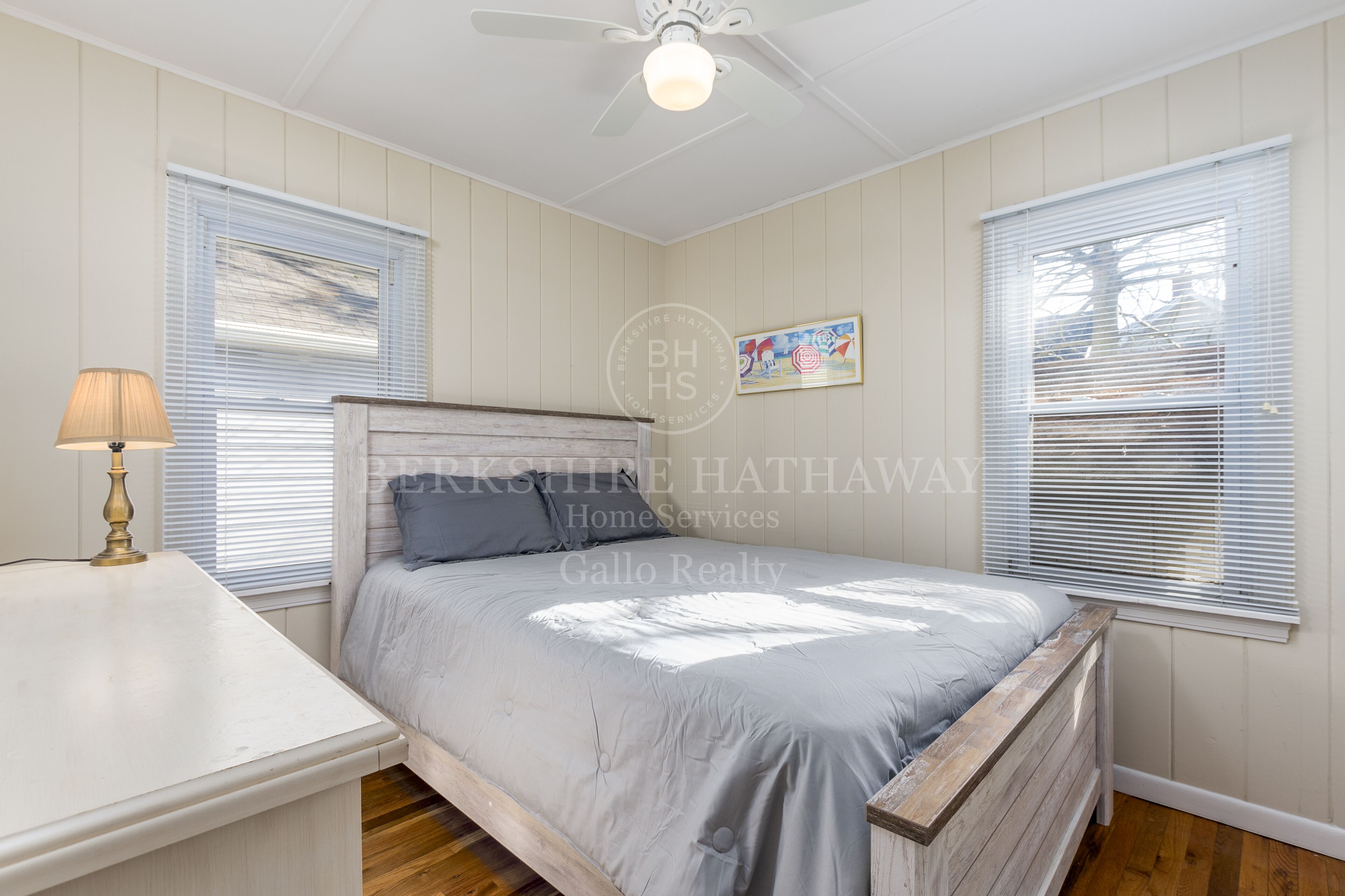 Un dormitorio con cama, mesita de noche, lámpara y ventilador de techo.