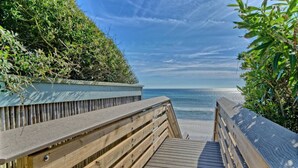 A wooden boardwalk leading to a beach with a clear view of the ocean.