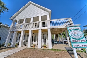 A two-story house with a balcony, a porch, and a sign indicating it is a vacation rental with 4 beds and 2 bathrooms.