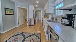 A modern kitchen with a sink, coffee maker, and a patterned rug.