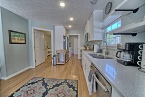 A modern kitchen with a sink, coffee maker, and a patterned rug. - A Block Away Bliss: Steps from Seaside & Sand! (Santa Rosa Beach)