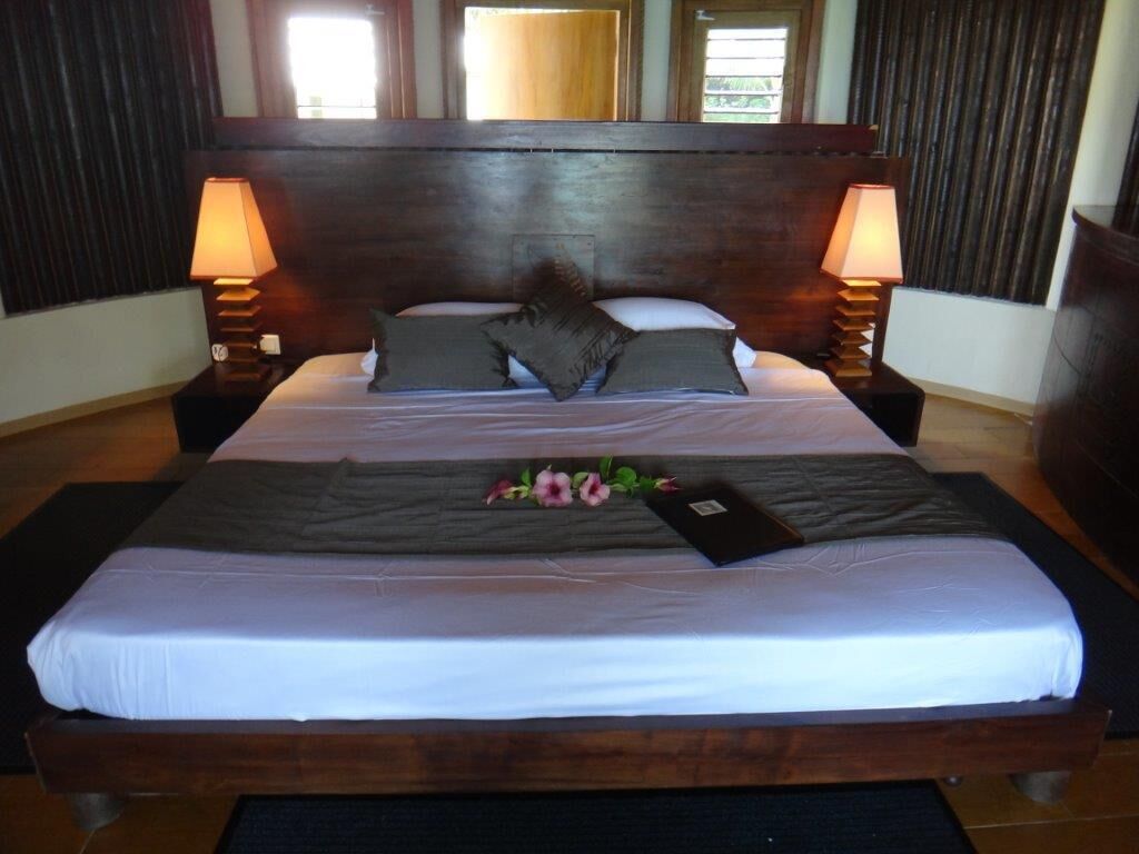 A large bed with a wooden headboard, two bedside lamps, and a floral arrangement on the bed.