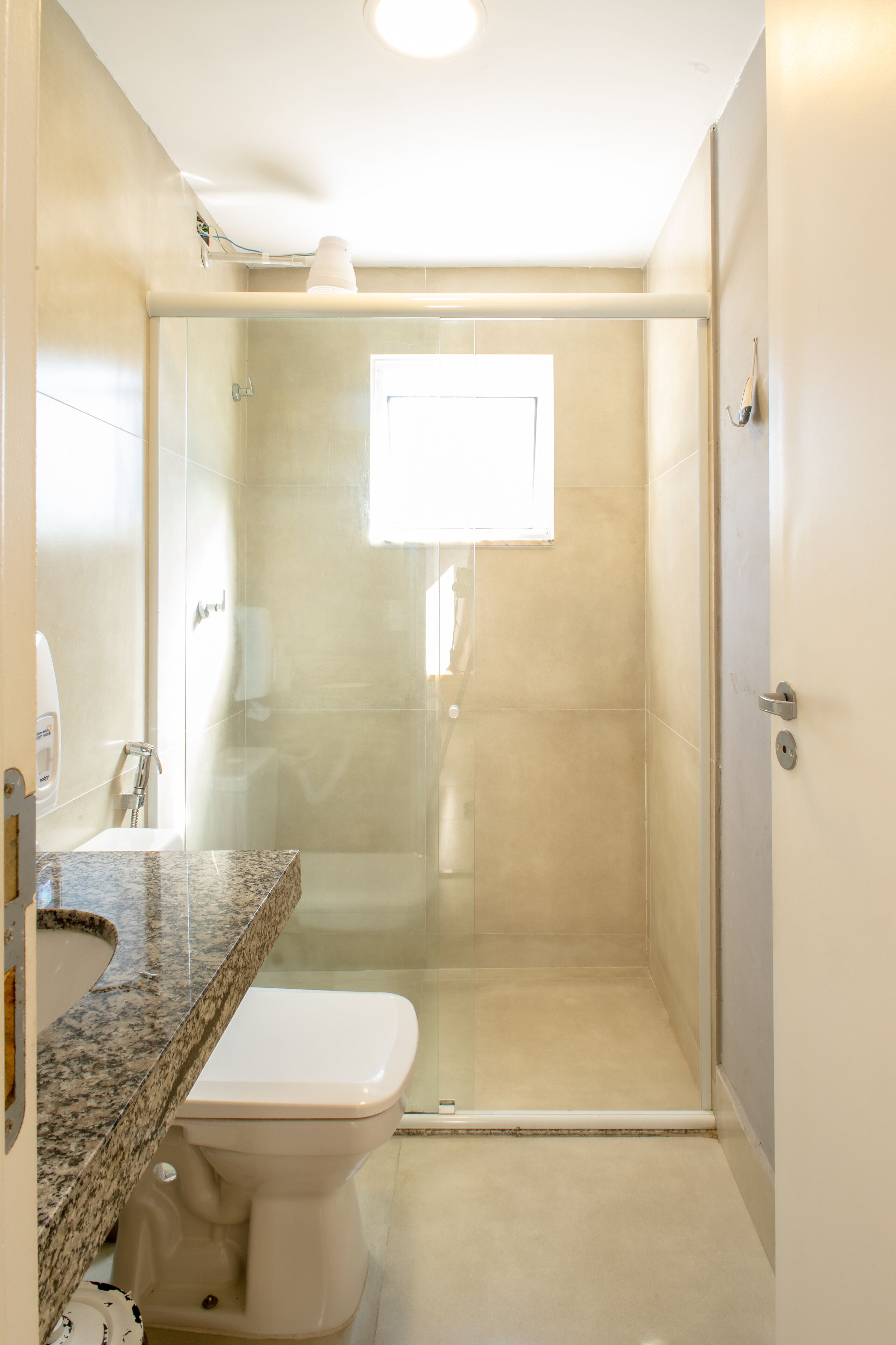 Een badkamer met douche, toilet en wastafel.