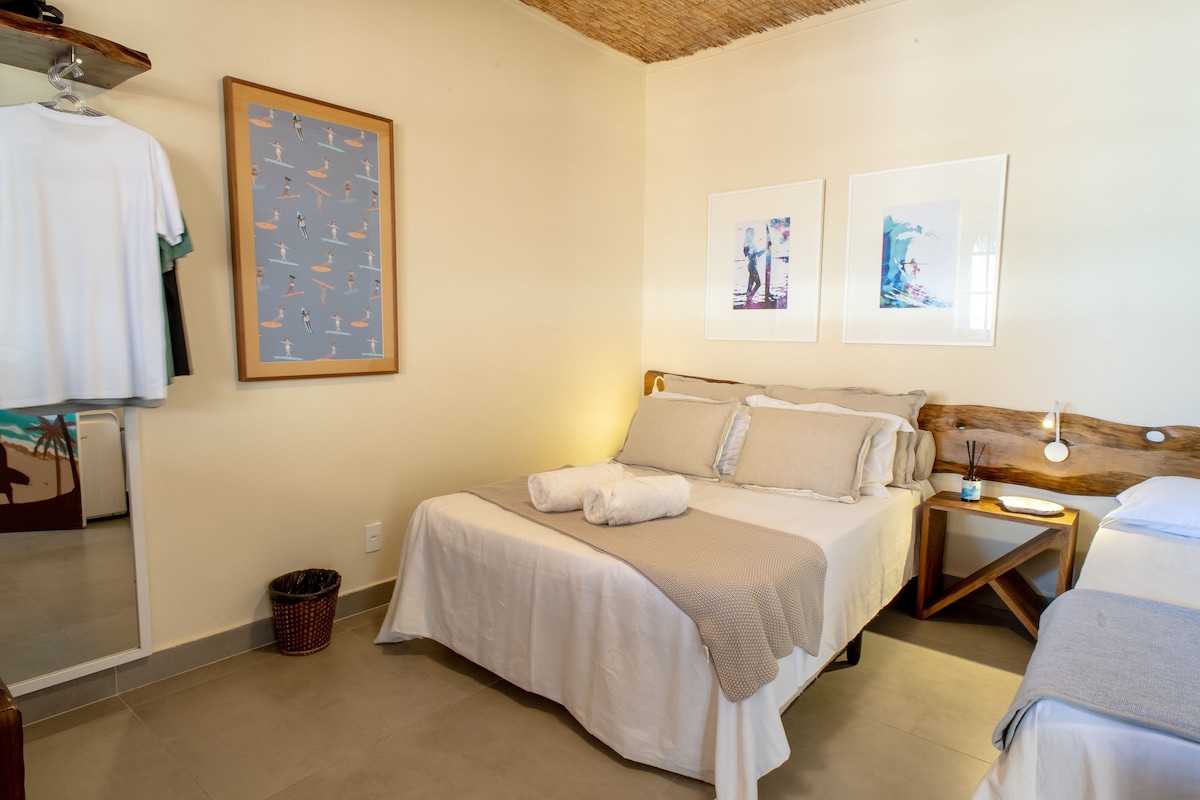 A bedroom with a bed, a nightstand, a framed picture, and a wall-mounted shelf.