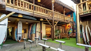 Un edificio de madera con balcón, tablas de surf y un mural.