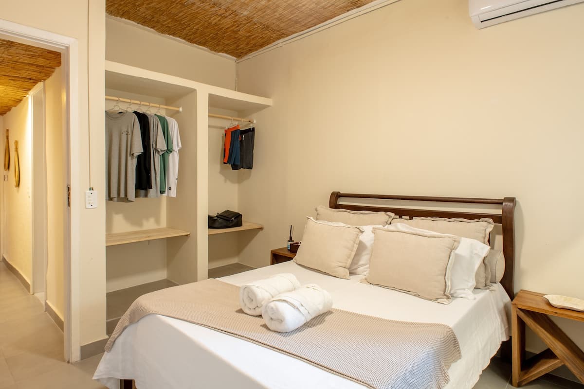 Quarto com cama, guarda-roupa e mesa de cabeceira.