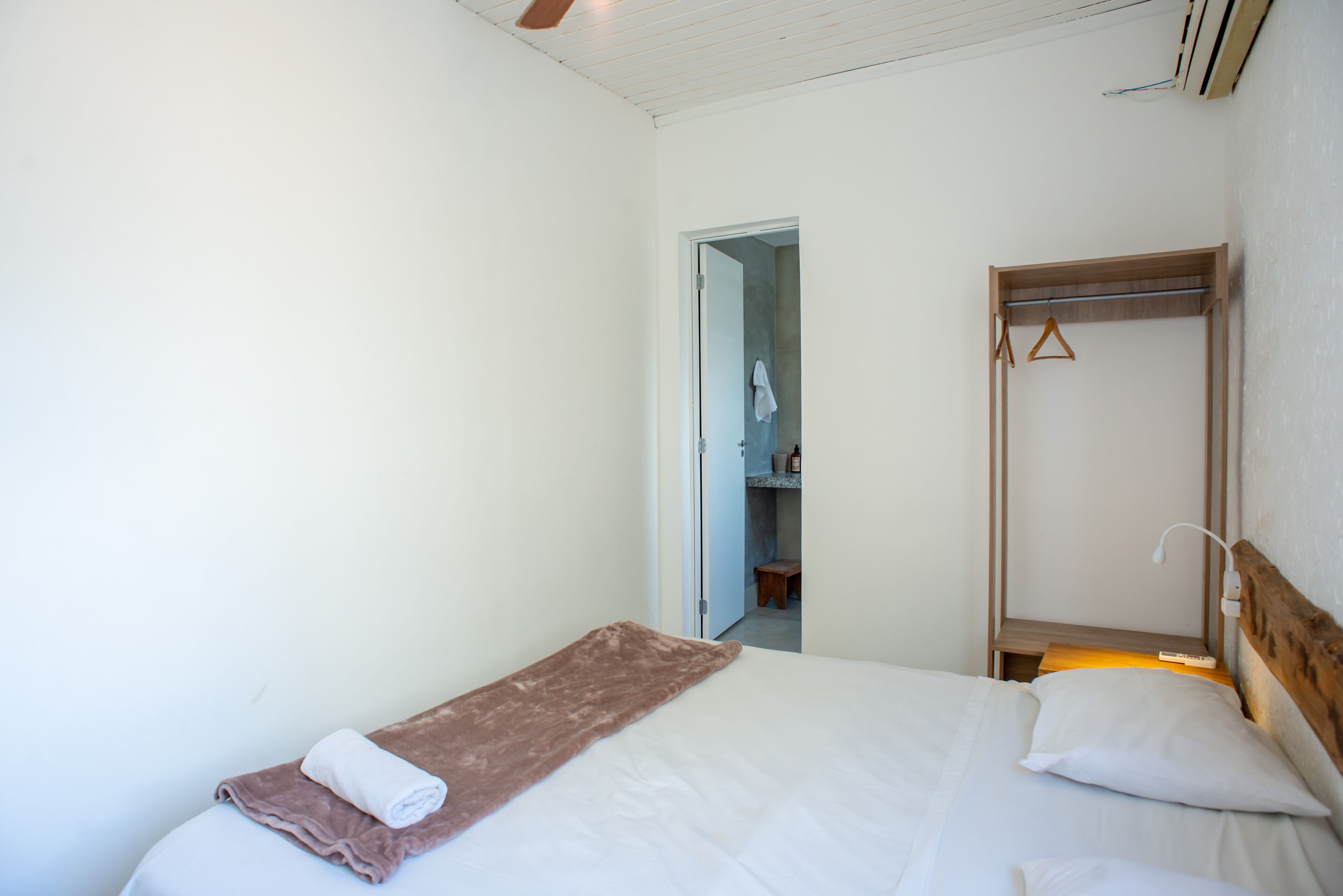 A bedroom with a bed, a wooden headboard, a bedside table with a lamp, and a door leading to a bathroom.