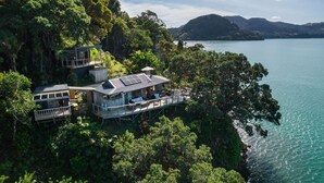 A secluded house with multiple decks and a view of a lake surrounded by dense forest and hills. - 'KIWI LODGE' - a beautiful, secluded rustic cabin (Totara North)