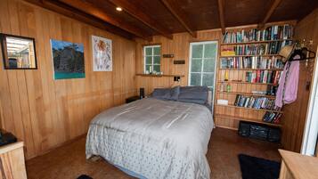 Un dormitorio con paneles de madera, una cama, una estantería y un ventanal.