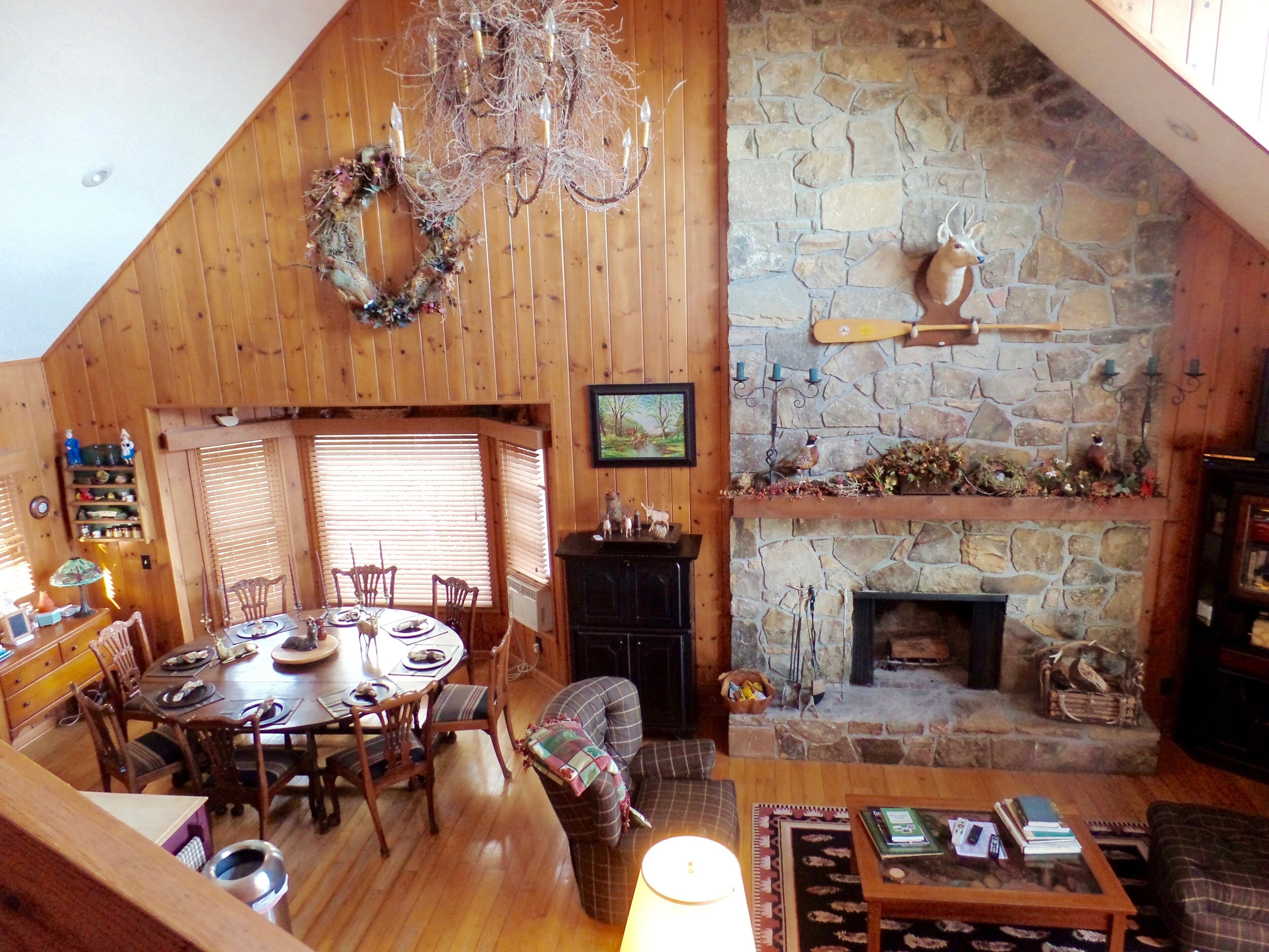 Un intérieur chaleureux, avec des éléments en bois, comprenant un coin repas, une cheminée et un mur en pierre.