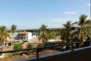 Zona residencial con casas y palmeras, vista desde un balcón con barandilla de metal.