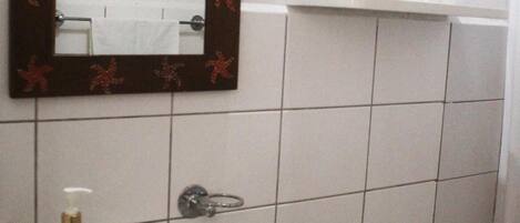 Ein Badezimmer mit einem Waschbecken mit Granitplatte, einem Spiegel mit Zierrahmen, einer Toilette und einem kleinen Regal darüber.