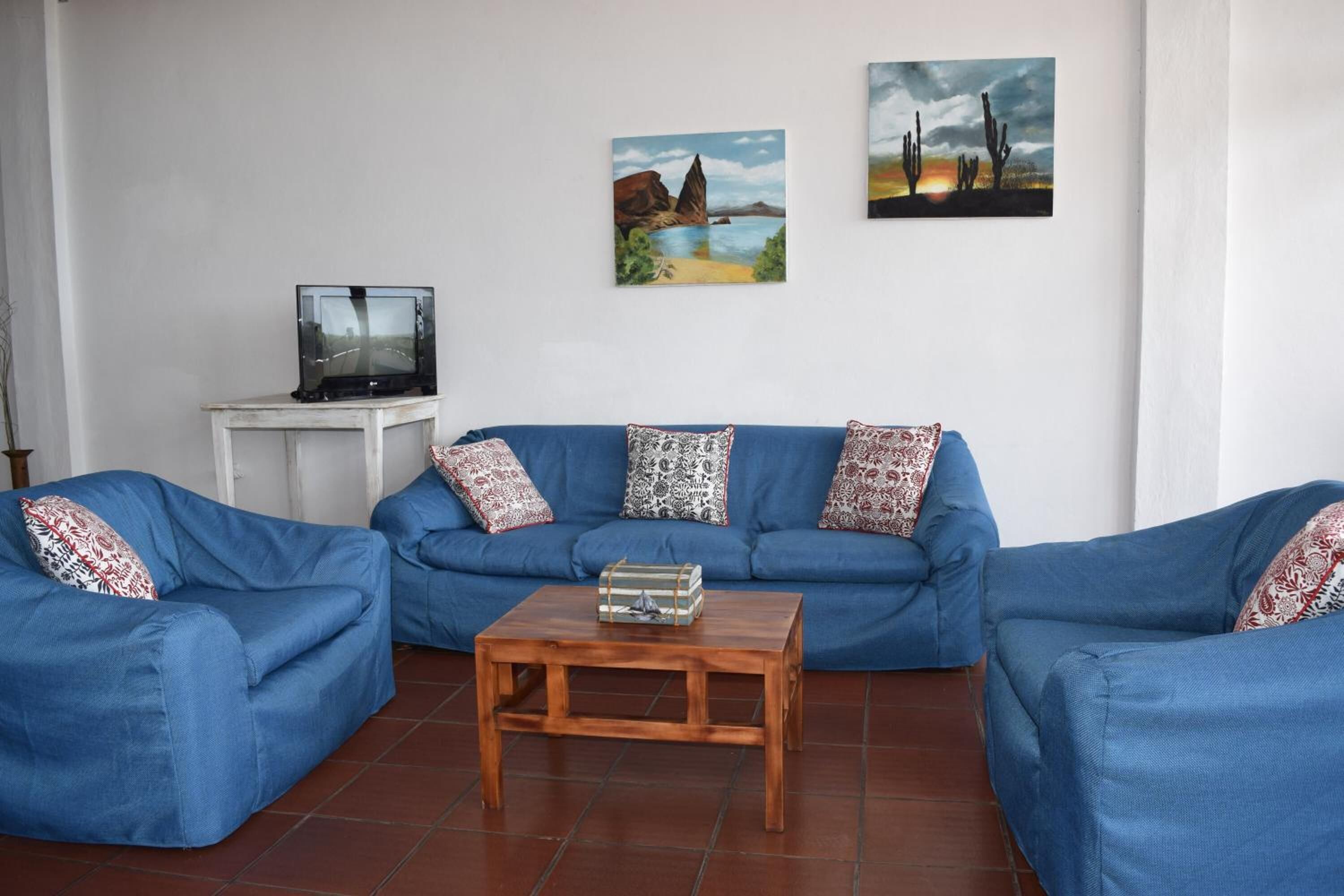 A living room with a blue sofa set, a wooden coffee table, and a television on a small table.