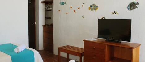 A hotel room with two beds, a TV, a wooden dresser, and a bench.