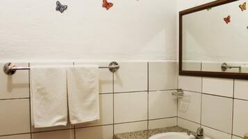 A bathroom with a white sink, a towel rack with two towels, and a mirror with butterfly decals on the wall.