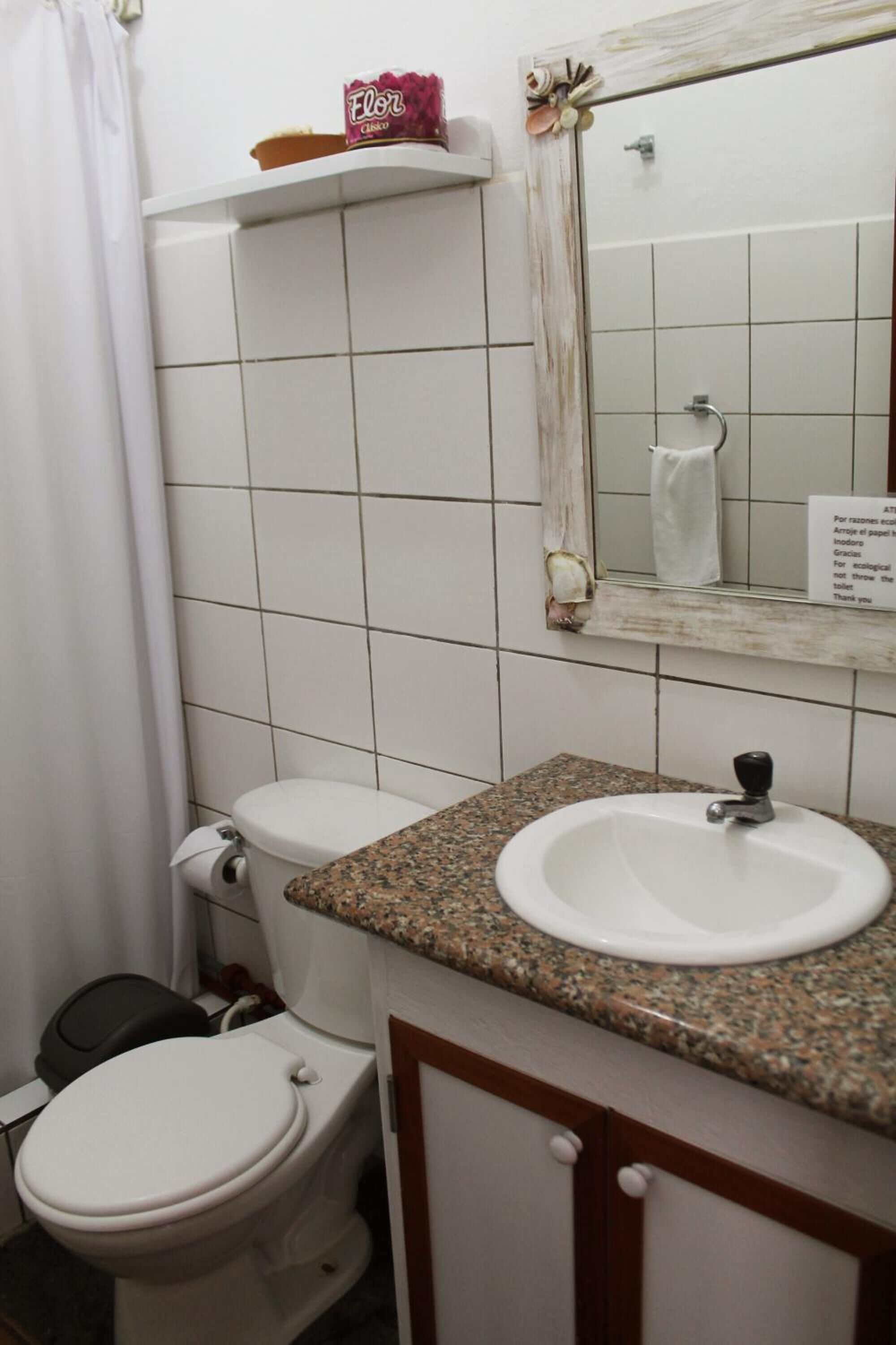 A bathroom with a white toilet, a sink with a granite countertop, and a mirror above the sink.
