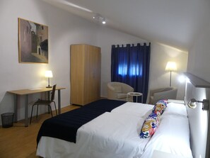 A hotel room with a bed, desk, chair, wardrobe, and two lamps. - Casa Rural Julio Vegas (Santiago del Campo)