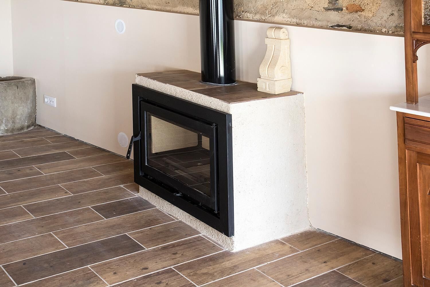 A room with a fireplace, tiled floor, and a wooden cabinet.