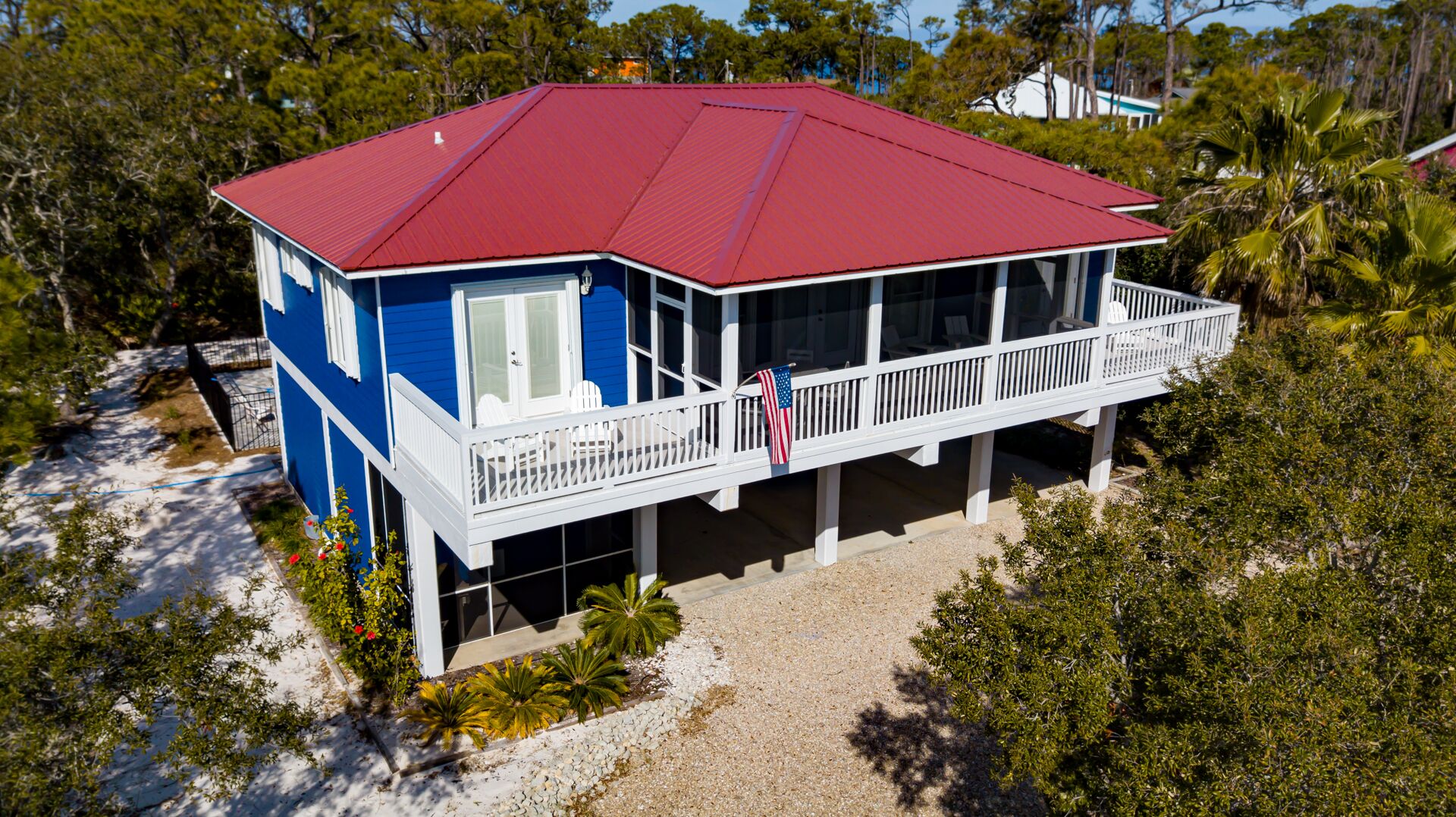 Une maison à deux étages avec un toit rouge, un balcon doté de balustrades blanches et un drapeau.