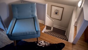 A room with a blue armchair, a staircase with a patterned floor, and a framed picture on the wall. - Sweet Spot in West Washington Park (Denver)