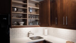 A kitchen with white subway tiles, a stainless steel sink, wooden cabinets, and a black refrigerator. - Sweet Spot in West Washington Park (Denver)