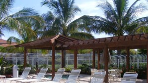 Ein überdachter Außenbereich mit weißen Loungesesseln und einer Pergola.
