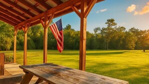 A wooden pavilion with a picnic table and an American flag.