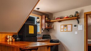 A kitchen with a wooden bar, stools, a refrigerator, and a stove.