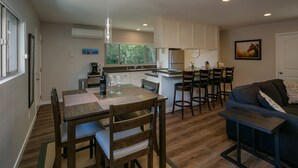 A compact kitchen with a dining area, a sofa, and a small table.