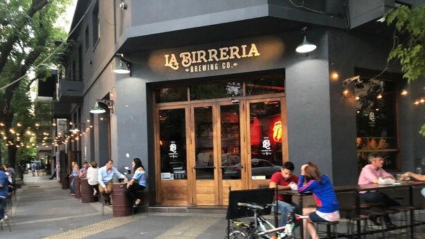 Un restaurante llamado "La Birreria Brewing Co." con terraza y bicicletas estacionadas afuera.