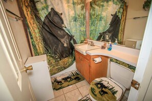 A bathroom with a bear-themed mural, a wooden vanity, a sink, and a toilet.