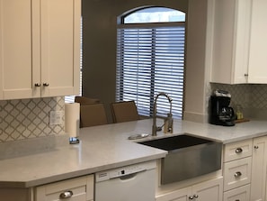 A modern kitchen with white cabinets, a stainless steel sink, and a built-in dishwasher.