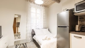 A compact hotel room with a bed, a small table, a refrigerator, a microwave, and a television. - Great brand new 1 bedroom apartment in the center of old Antibes (Antibes)