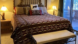Ein Schlafzimmer mit einem großen Bett, zwei Nachttischlampen, einem Deckenventilator und Blick ins Freie durch ein Fenster.