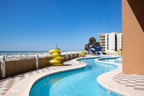 A pool area with multiple lanes, a white fence, and a clear blue sky.