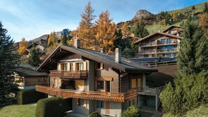 A chalet-style building with a balcony, surrounded by well-maintained hedges and trees. - Orchidée 111 by Interhome (Verbier)