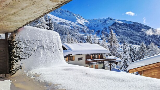 A snow-covered mountain landscape with a wooden cabin and a building with a balcony. - Orchidée 111 by Interhome (Verbier)