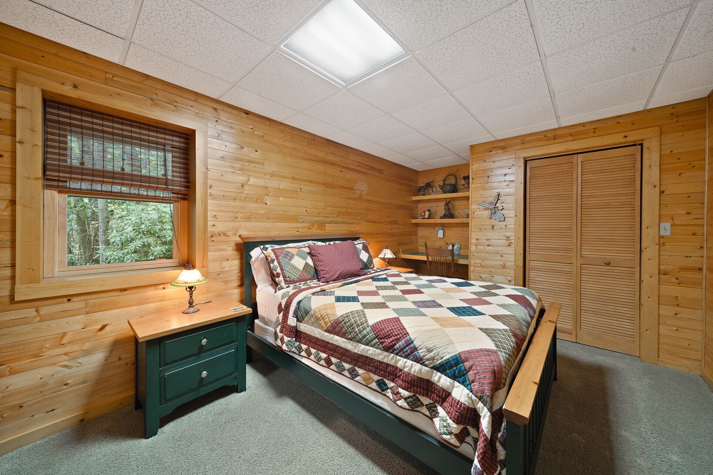 Camera da letto con pannelli in legno, un letto, un comodino e una finestra.